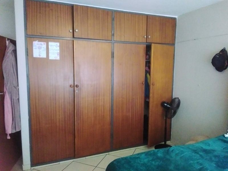 Bedroom featuring floor-to-ceiling built-in wooden cupboards and tiled flooring, offering ample storage space.