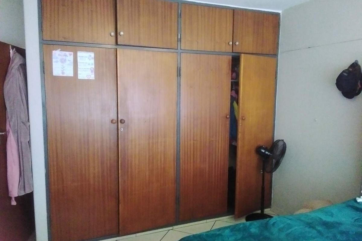 Bedroom featuring floor-to-ceiling built-in wooden cupboards and tiled flooring, offering ample storage space.