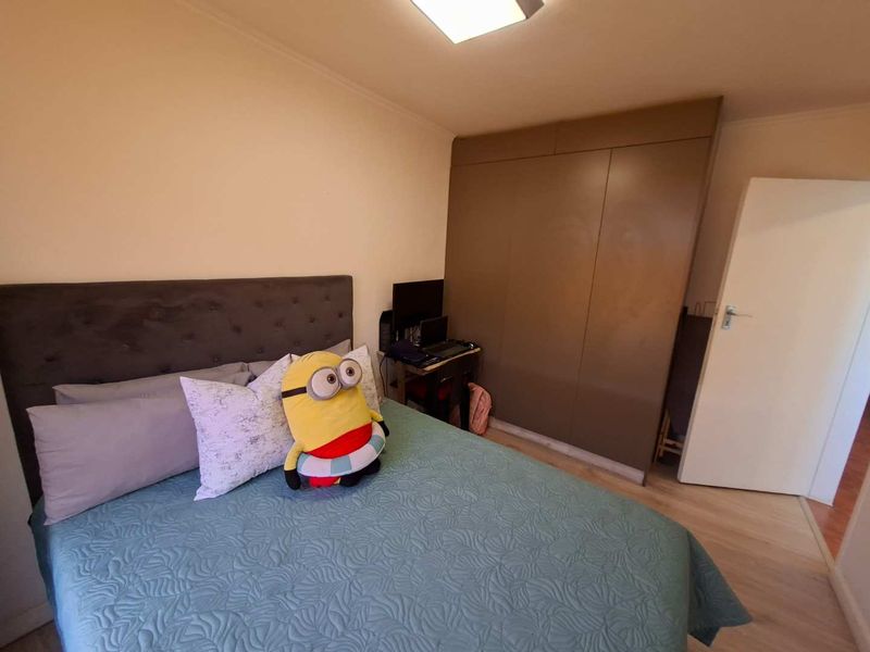 A bedroom featuring laminate flooring, a built-in wardrobe, and a flush mount ceiling light.