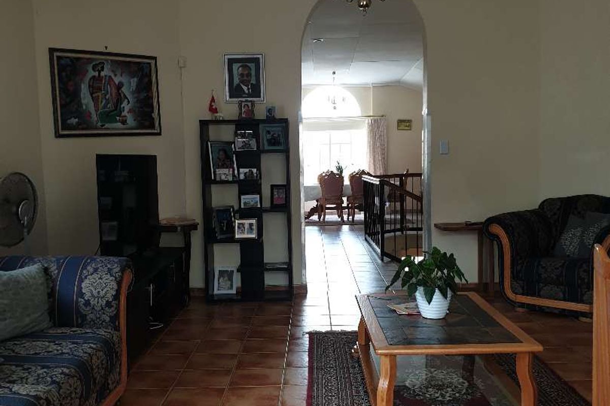 A spacious living room featuring terracotta floor tiles and an arched doorway leading to an adjacent dining area.