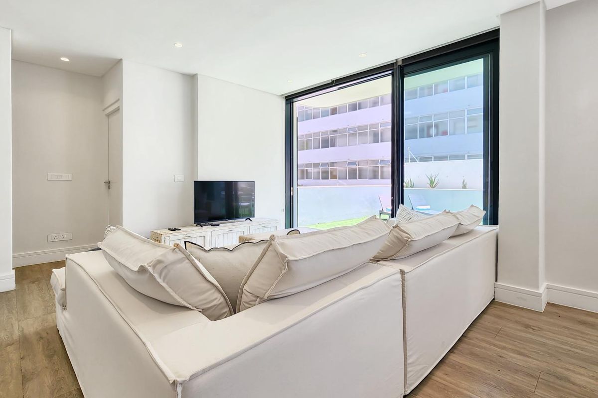 Bright and modern living room featuring large sliding glass doors that open onto a private patio area, creating a seamless indoor-outdoor flow.