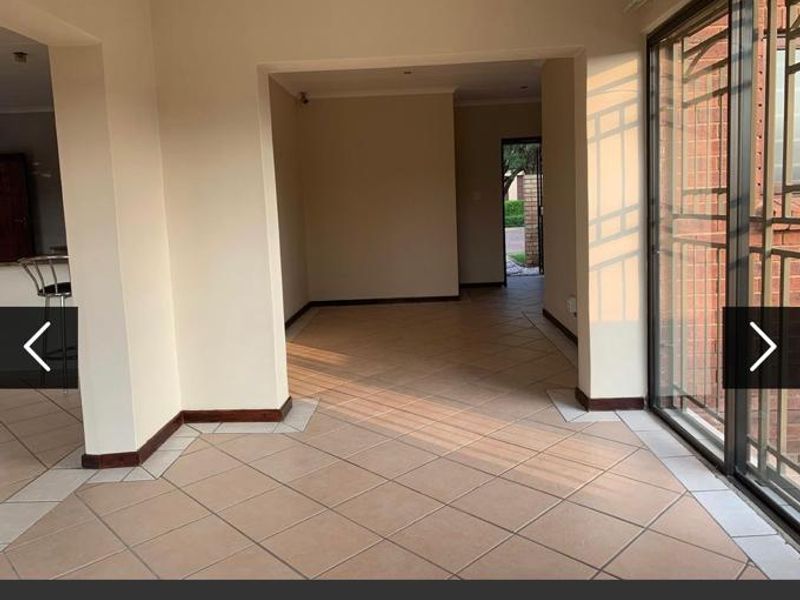 Spacious open-plan living area featuring neutral tiled flooring and large sliding glass doors that provide access to the exterior.
