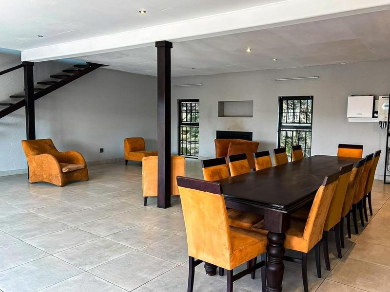 Spacious open-plan living and dining area featuring large floor tiles, a built-in fireplace, and an integrated staircase leading to the upper level.