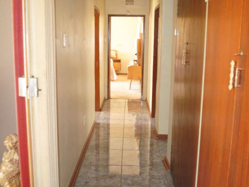 A functional hallway featuring tiled flooring and extensive built-in wooden cabinetry for storage, connecting various rooms within the home.