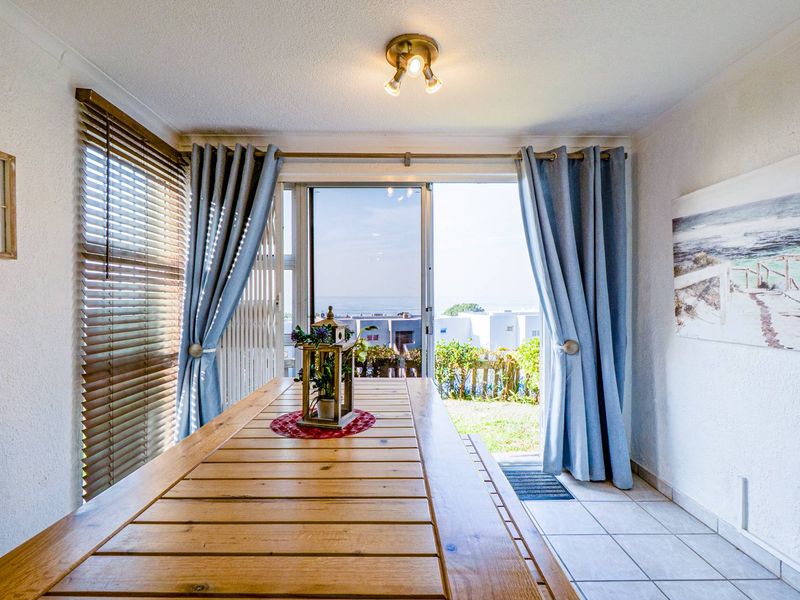 Bright dining area featuring tiled flooring, venetian blinds, and a sliding glass door providing direct access to the outdoor patio and garden.