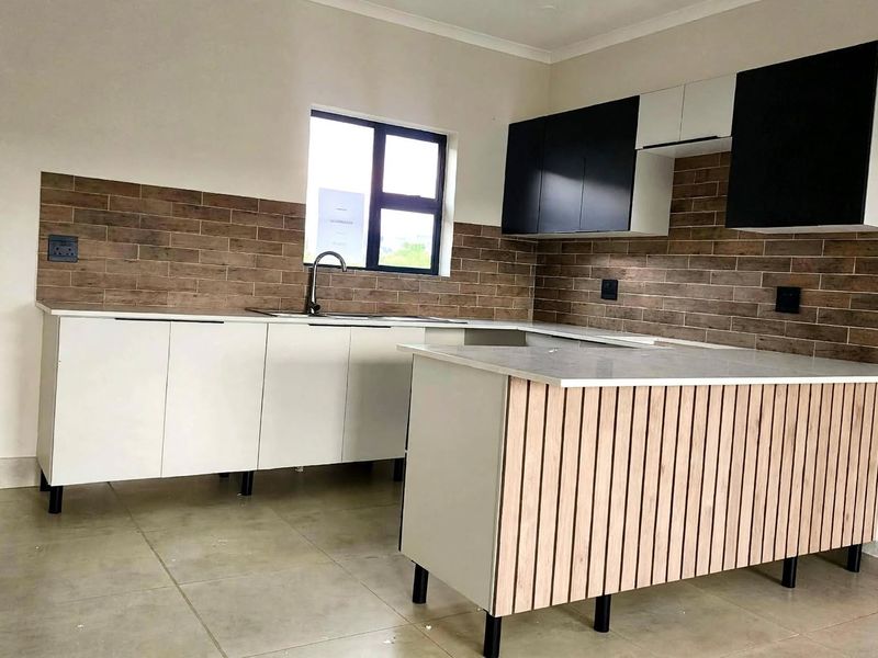 Modern kitchen featuring sleek two-tone cabinetry, a functional island with wood-slat detailing, stone countertops, and a stylish tiled backsplash.