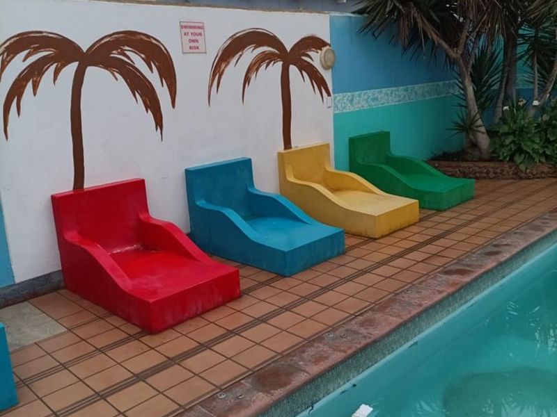 Outdoor pool area featuring a tiled deck, built-in concrete seating, and a boundary wall with painted palm tree murals.