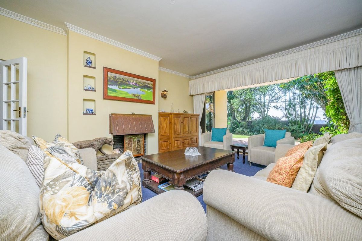 Spacious living room featuring a fireplace with built-in wall niches, crown molding, and large sliding glass doors providing direct access to the garden.