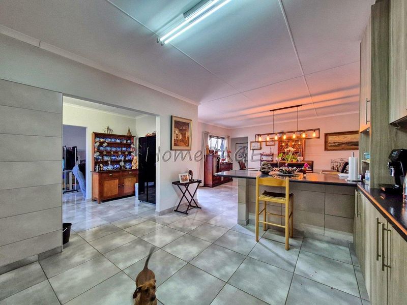 Spacious open-plan kitchen and living area featuring tiled flooring, modern cabinetry, and a central kitchen island with breakfast bar seating.