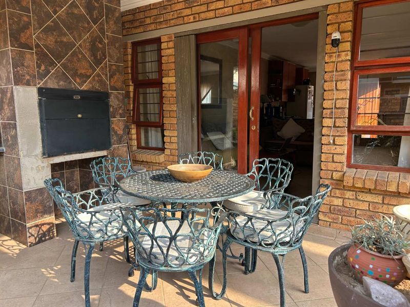 Covered patio area featuring a built-in braai, tiled flooring, and direct access to the interior through sliding glass doors.