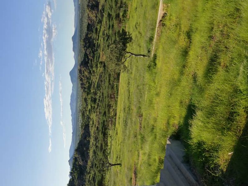 Expansive scenic view overlooking a natural landscape with rolling hills and mountains, viewed from a raised concrete patio area.