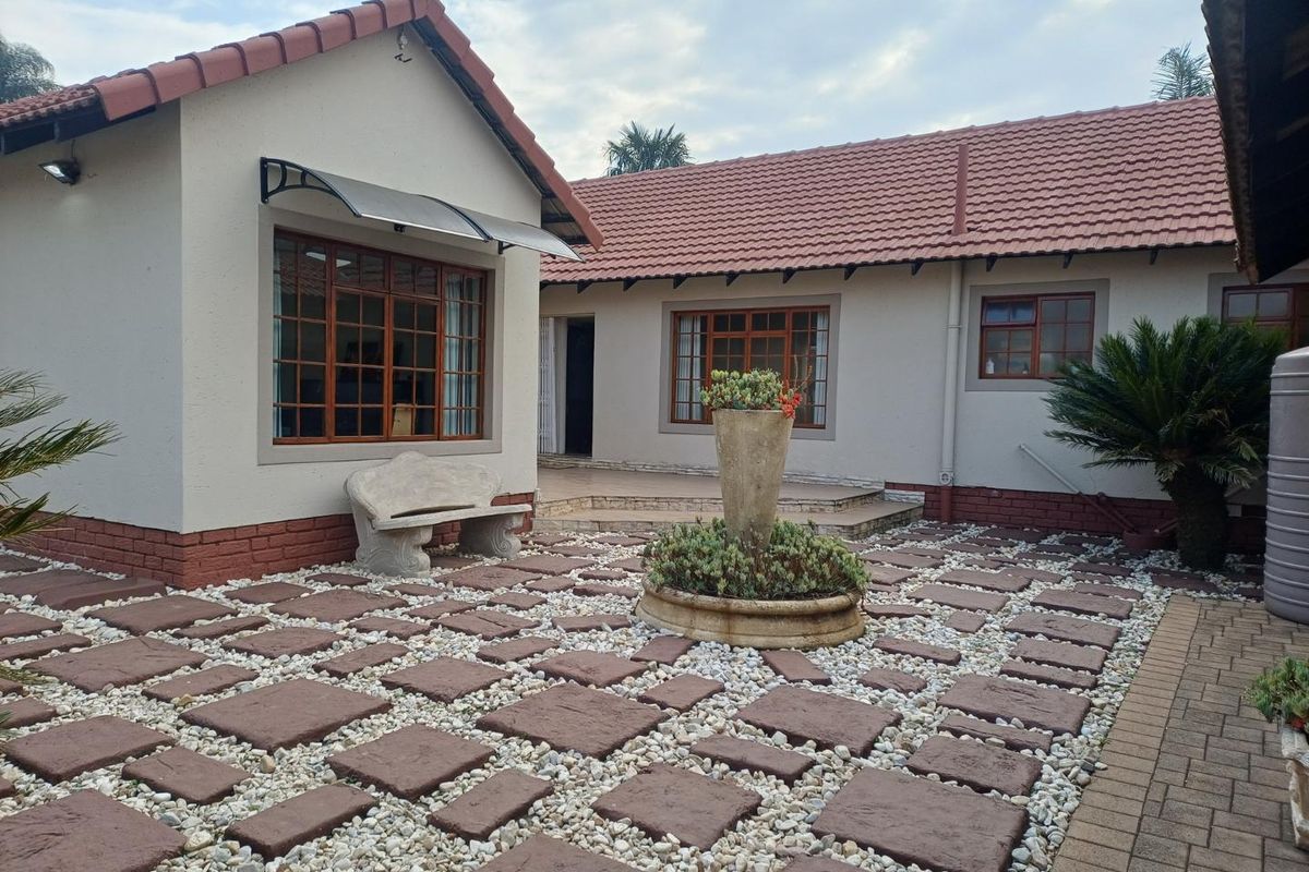A well-maintained rear courtyard featuring stone paving, a central fountain, and classic terracotta roof tiles with timber-framed windows.