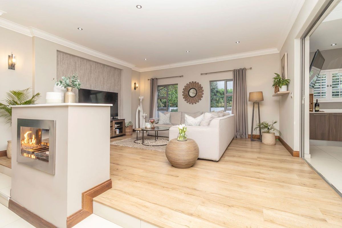 Spacious living room featuring a modern built-in fireplace, recessed downlights, and light-toned laminate flooring, creating a bright and inviting atmosphere.
