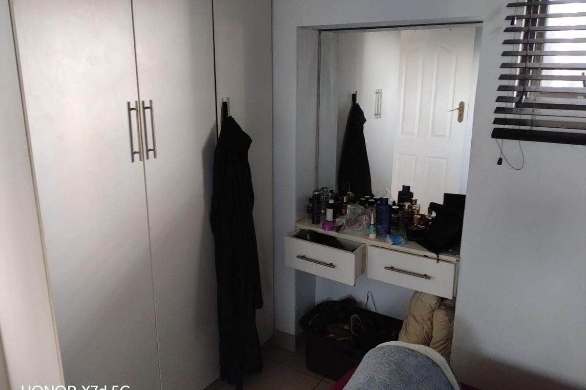 A bedroom area featuring built-in floor-to-ceiling wardrobes and a recessed vanity station with integrated drawers and a large mirror.