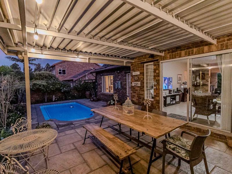 A covered outdoor patio area featuring paved flooring, brick walls, and direct access to the interior living space through sliding glass doors.