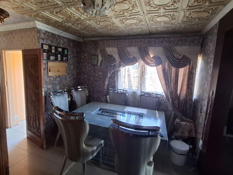 Dining room featuring decorative ceiling tiles, tiled flooring, and a solid wood door, offering a traditional aesthetic ready for modern updates.