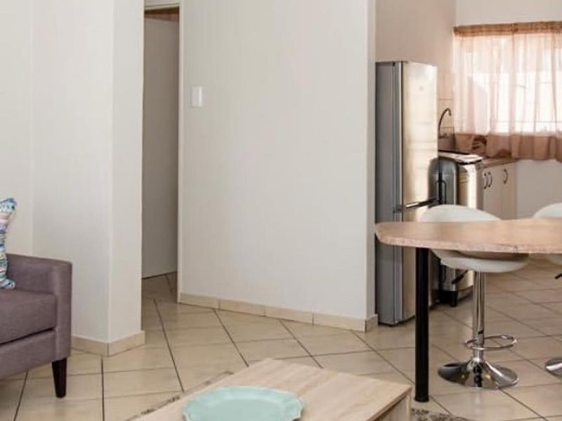 Open plan living area featuring tiled flooring and a compact kitchen space with built-in cabinetry and sink.