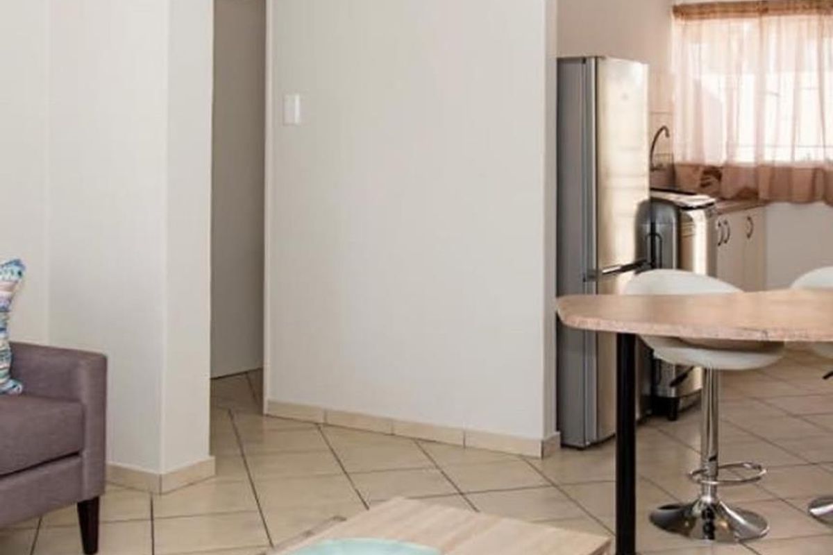 Open plan living area featuring tiled flooring and a compact kitchen space with built-in cabinetry and sink.