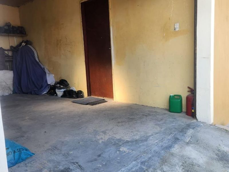 A functional garage space featuring concrete flooring and an internal access door, currently in need of cosmetic refurbishment and wall maintenance.