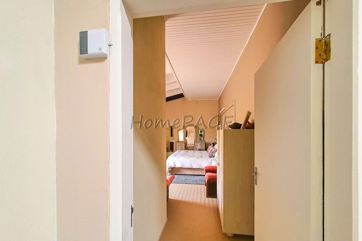 A view through a doorway into a bedroom featuring a sloped ceiling and carpeted flooring.