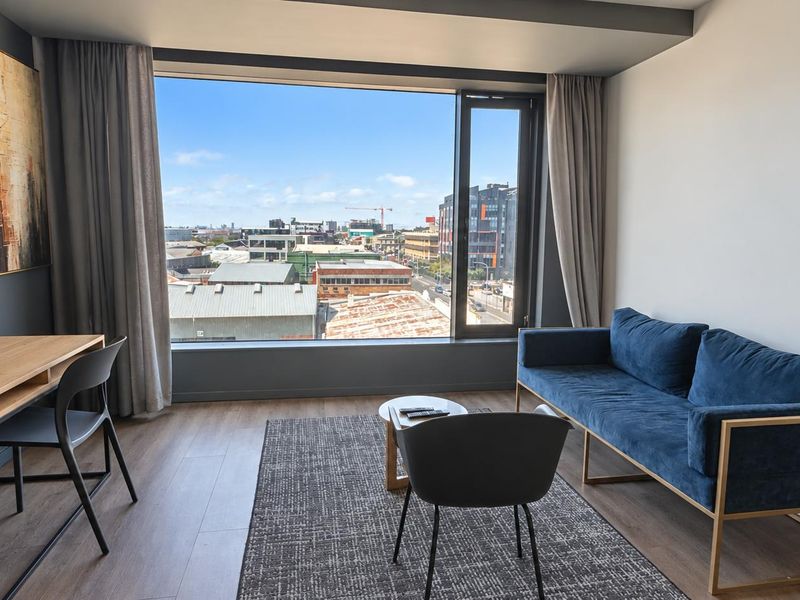 Modern living area featuring large picture windows with expansive urban views, neutral walls, and durable laminate flooring.