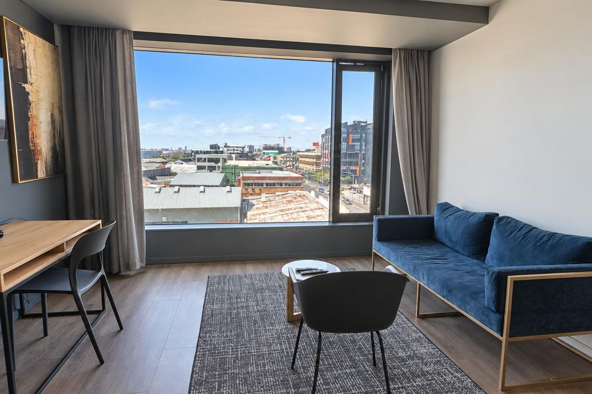Modern living area featuring large picture windows with expansive urban views, neutral walls, and durable laminate flooring.
