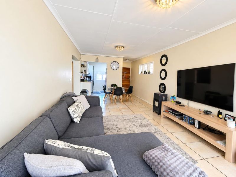 An open-plan living and dining area featuring tiled flooring and neutral walls, providing a functional and connected space for daily living.