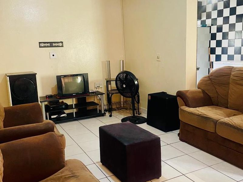A living room area featuring tiled flooring and coved ceilings, requiring cosmetic updates to the wall finishes.