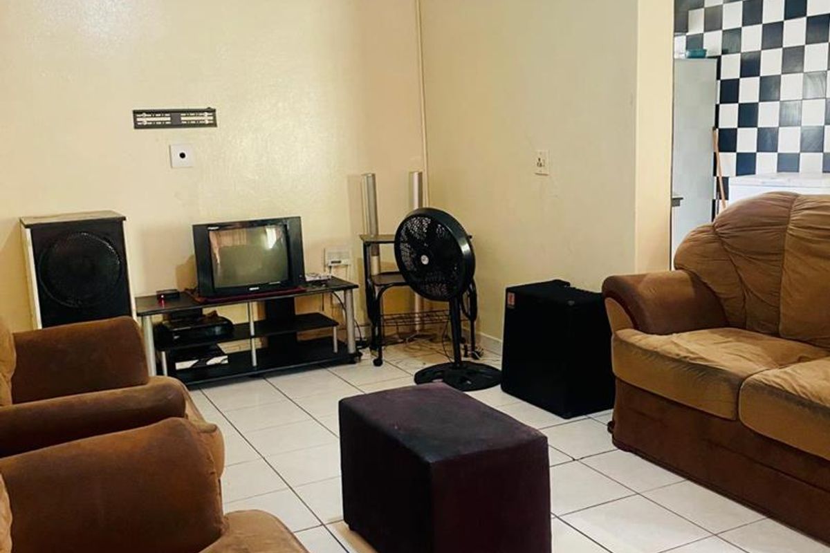 A living room area featuring tiled flooring and coved ceilings, requiring cosmetic updates to the wall finishes.
