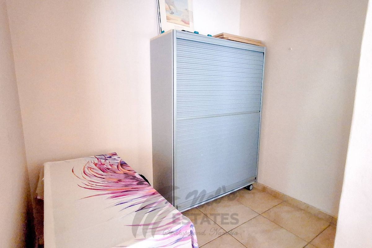 A small, functional room featuring tiled flooring, suitable for use as a bedroom or storage space.