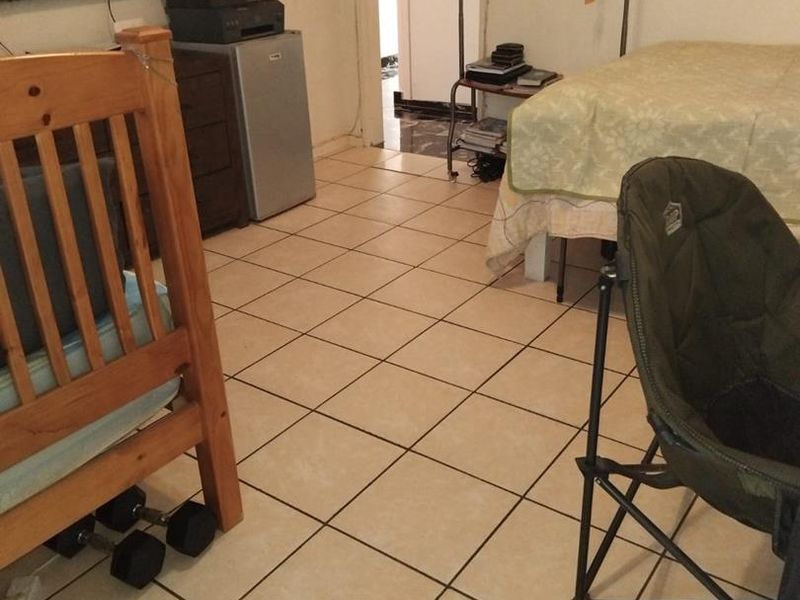 A bedroom featuring tiled flooring and a doorway leading to an adjacent space.