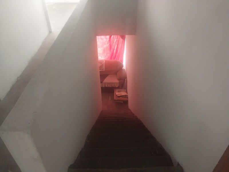 A view looking down a concrete staircase in a hallway, showing basic structural finishes and limited natural light.