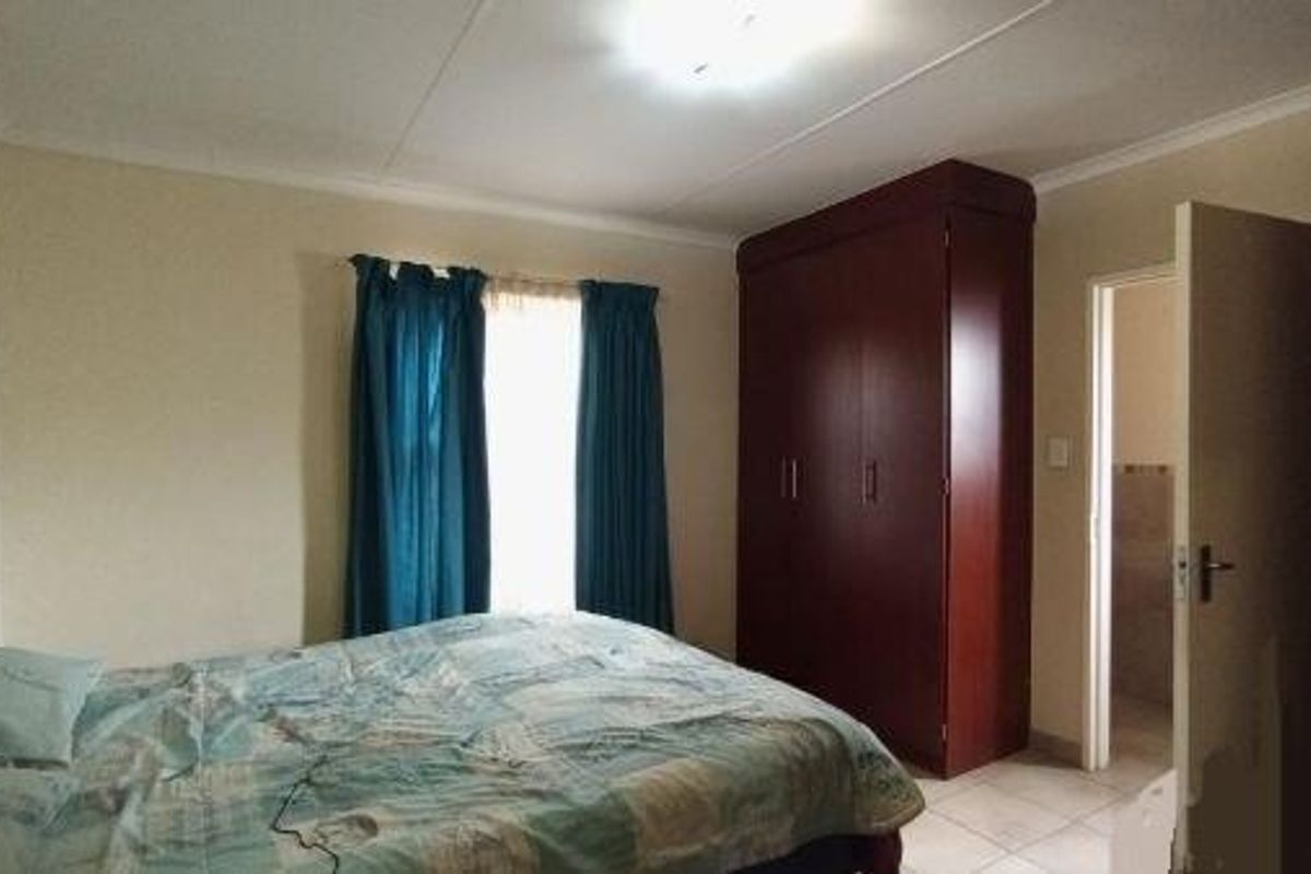A functional bedroom featuring a built-in wardrobe, tiled flooring, and coved ceiling, providing a practical and comfortable living space.