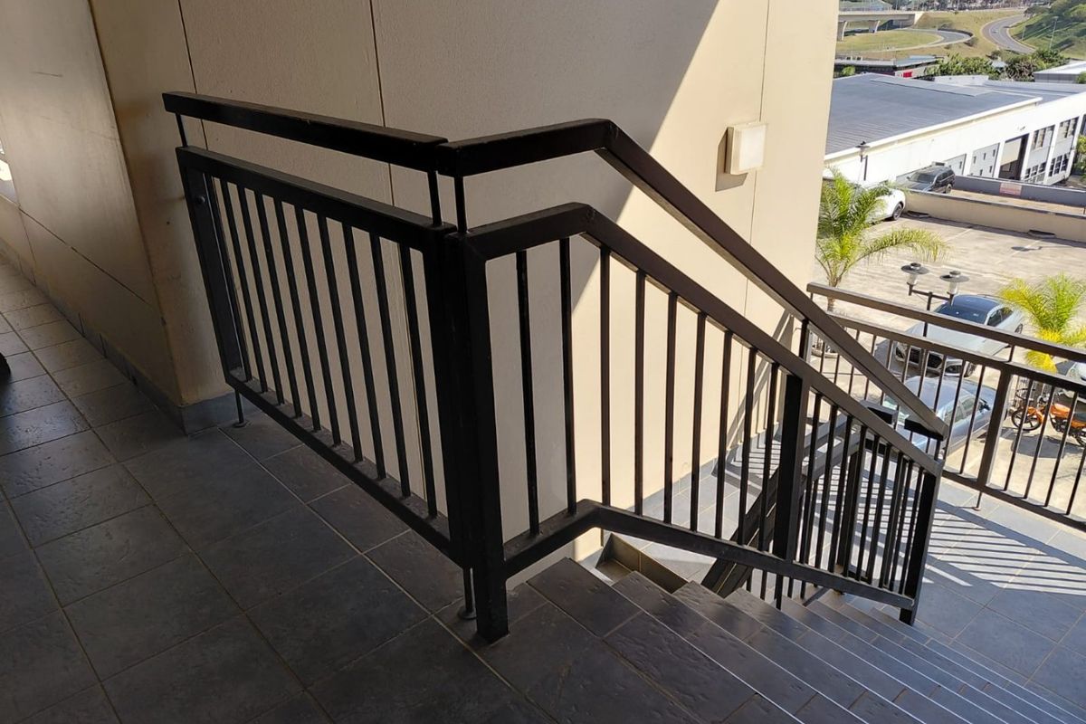 Exterior staircase with metal balustrade and tiled steps, providing access to the apartment level.