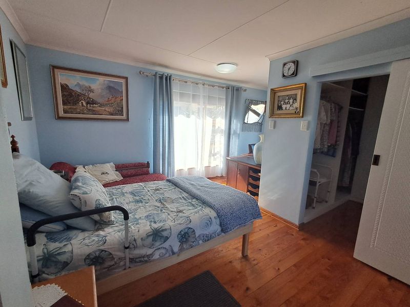 A bedroom featuring timber flooring, a built-in wardrobe, and a sliding glass door providing access to the exterior.