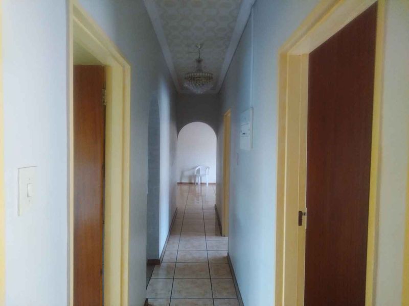A functional hallway featuring tiled flooring, arched architectural details, and multiple wooden door frames leading to adjacent rooms.