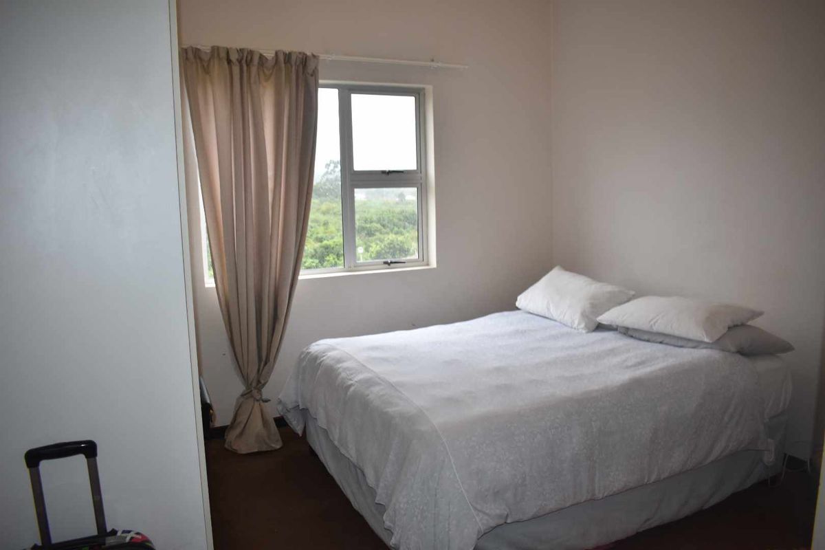 A functional bedroom featuring a built-in wardrobe and a window with natural light, providing a comfortable space for rest.