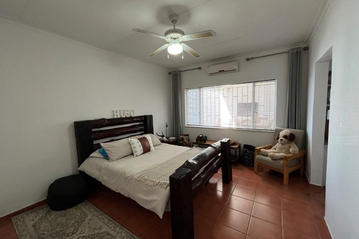 A bedroom featuring tiled flooring, a ceiling fan, and a wall-mounted air conditioning unit.