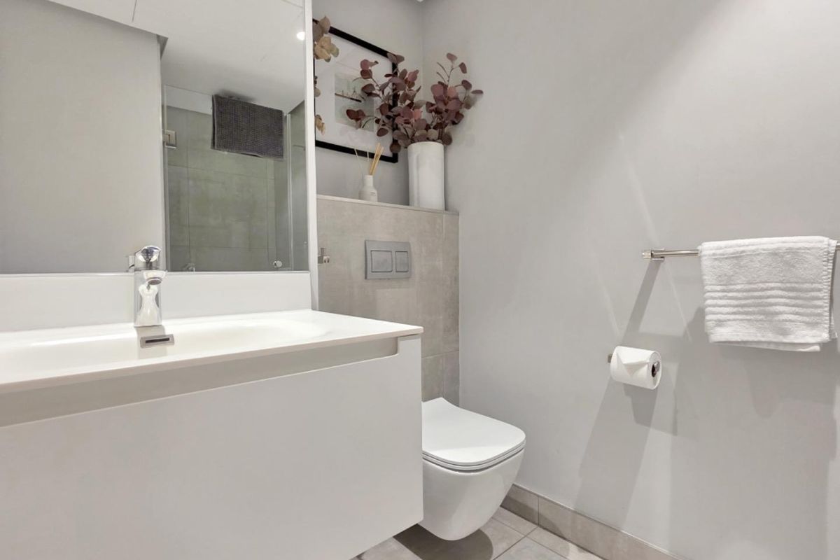 Modern bathroom featuring a wall-hung toilet with concealed cistern, sleek vanity basin with mixer tap, and neutral tiled finishes.