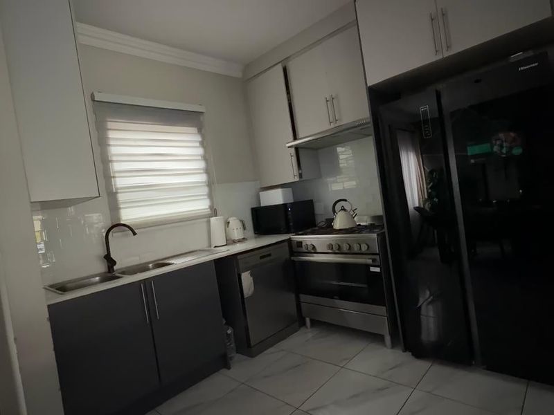 Modern kitchen featuring sleek cabinetry, stainless steel appliances, gas stove, and tiled flooring, offering a functional and contemporary cooking space.