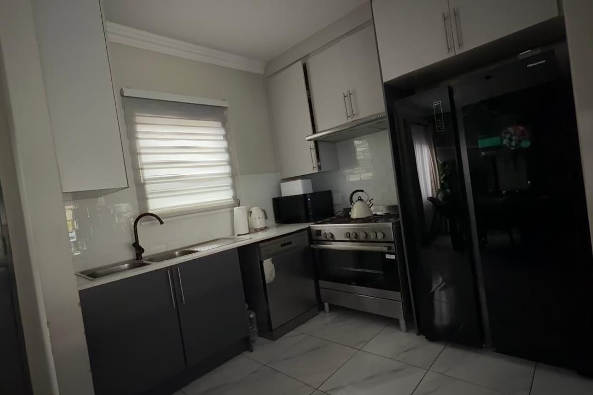Modern kitchen featuring sleek cabinetry, stainless steel appliances, gas stove, and tiled flooring, offering a functional and contemporary cooking space.