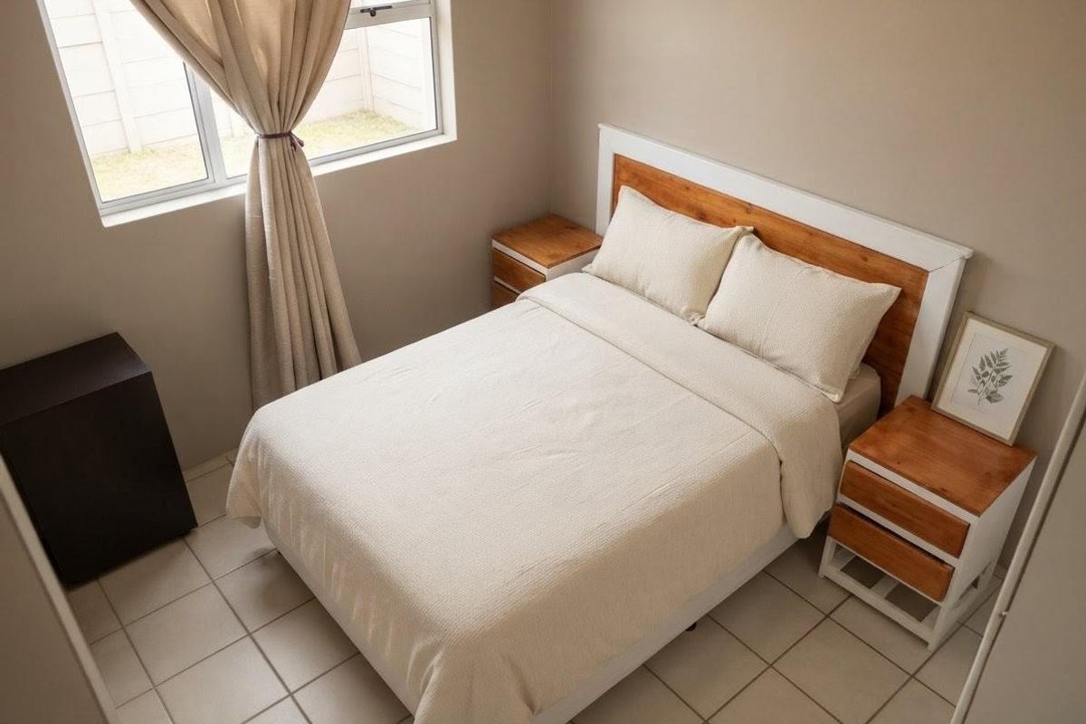 A well-maintained bedroom featuring neutral wall tones, tiled flooring, and a large window allowing for natural light.