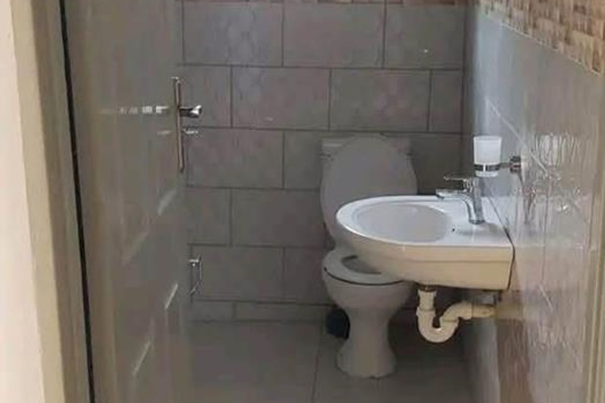 A compact bathroom featuring tiled walls and flooring, equipped with a wall-mounted basin and a standard toilet.