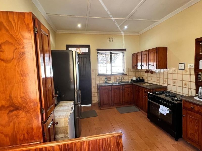 A functional kitchen featuring traditional wooden cabinetry, tiled backsplash, gas hob, and built-in oven, offering a classic aesthetic with practical storage and workspace.