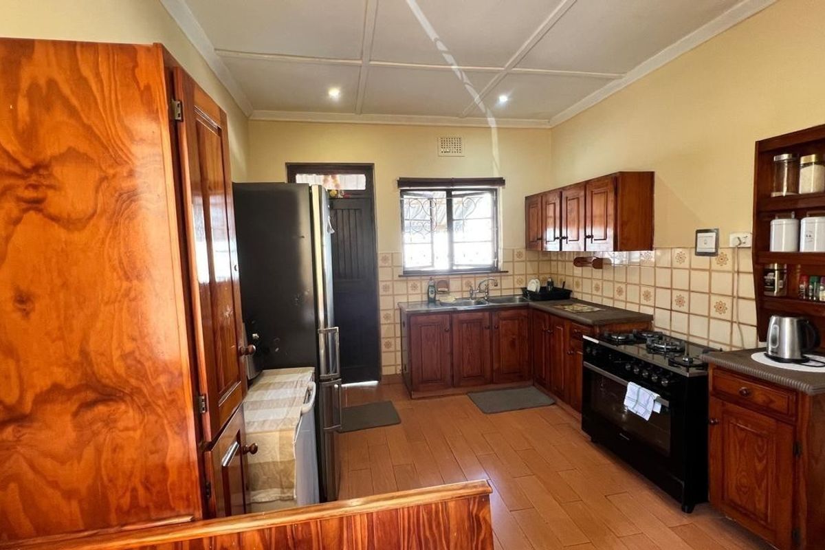 A functional kitchen featuring traditional wooden cabinetry, tiled backsplash, gas hob, and built-in oven, offering a classic aesthetic with practical storage and workspace.