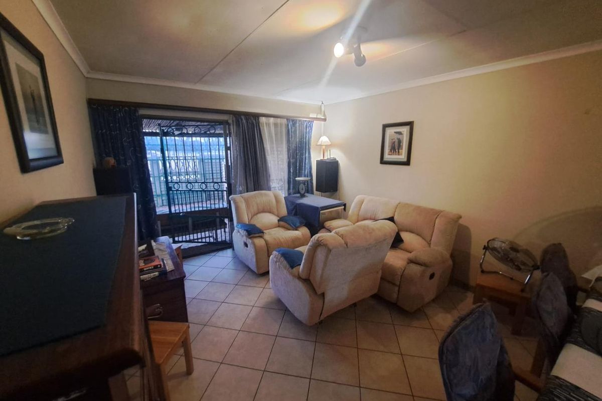 A living room featuring tiled flooring and a sliding glass door with security gate leading to an outdoor area.