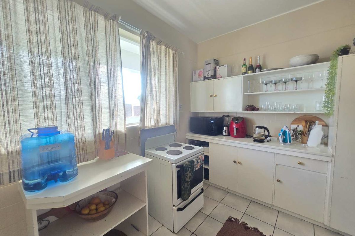 A functional kitchen featuring tiled flooring, built-in cabinetry with open shelving, and a freestanding electric stove, offering a practical layout for daily use.