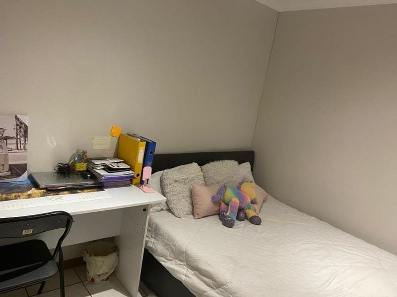 A compact bedroom featuring tiled flooring and neutral wall finishes, suitable for a single bed and study area.