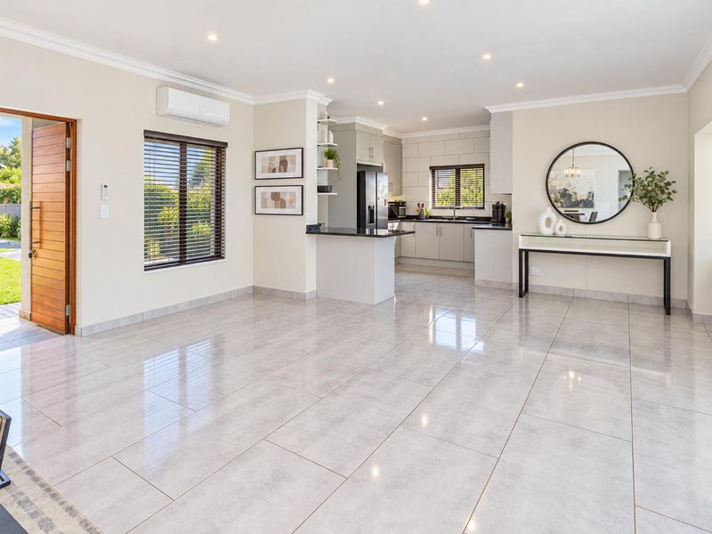 Spacious open-plan living area featuring polished porcelain tiles, recessed lighting, a modern kitchen with granite countertops, and direct access to the garden.