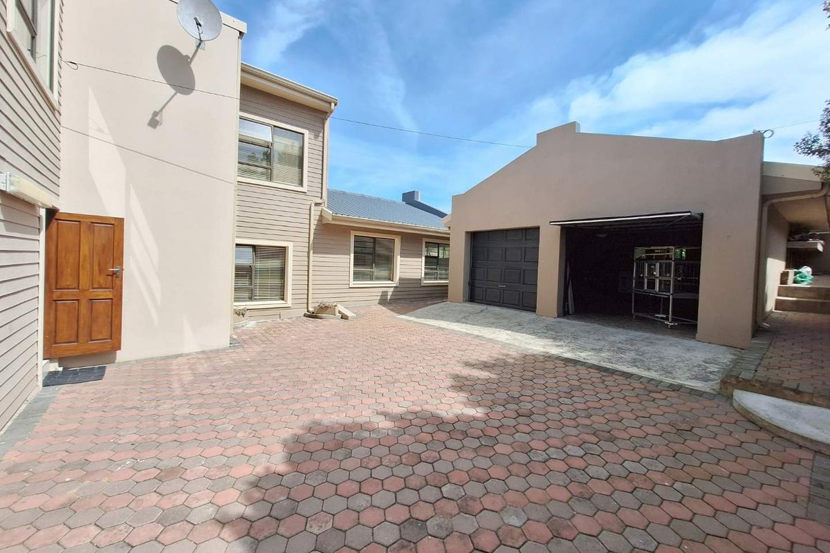 A paved courtyard area featuring a double garage with a sectional door and access to the main house structure.